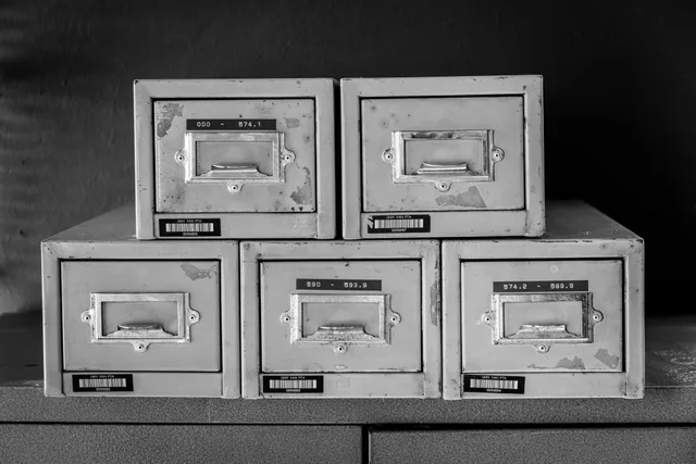 A set of five vintage metal file cabinets, aged and worn, displayed in black and white. Data brokers, people-search sites, credit bureaus, ad-tech platforms, public records, and identity services compared